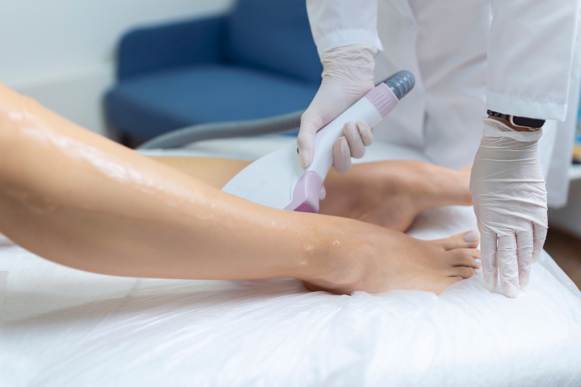 Beautician removes hair on beautiful female legs using a laser.